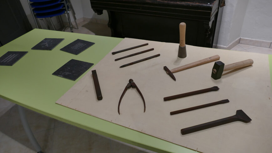 Foto degli attrezzi sul tavolo per la lavorazione della pietra e lastrine in ardesia (Museo Cenova)
