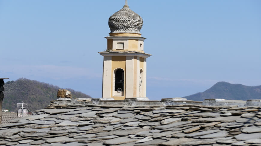 Tipico tetto in “ciappe” di ardesia oltre il quale è visibile il campanile della parrocchiale di San Martino (Rezzo)